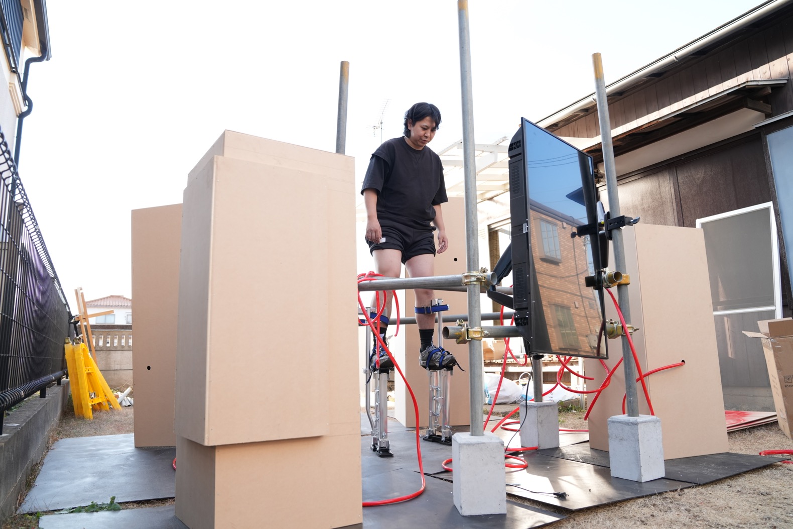 アトリエでの制作の様子。鉄製の竹馬をテスト装着する。